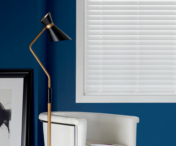 white composite blinds next to white fabric chair and modern lamp