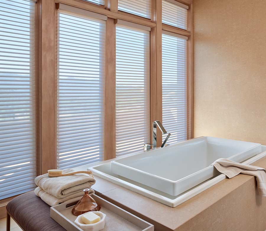 master bathroom sunken tub next to privacy shades framed with warm wood