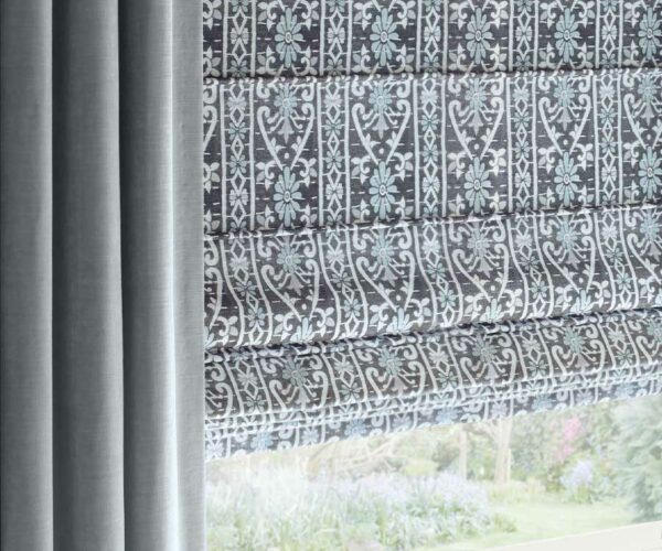 plush blue drapes framing blue and gray and white patterned roman shades