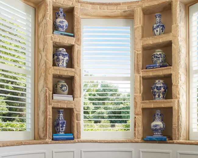 white plantation shutters on bay window with stone built ins