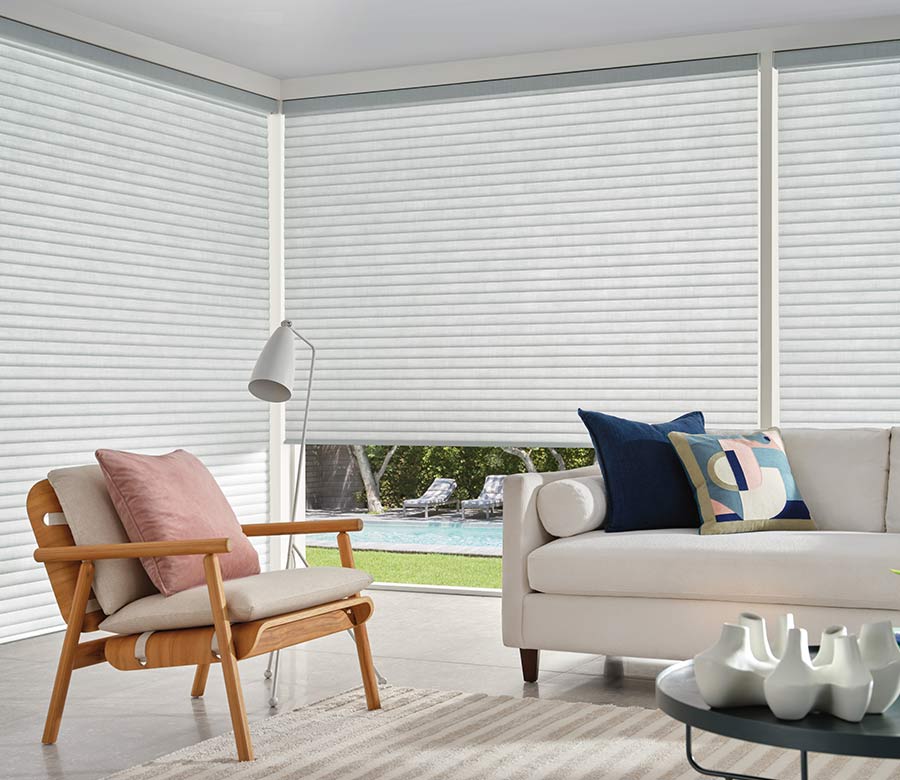 contemporary wood arm chair covered with beige pillow in front of corner windows and window shades overlooking outside pool area